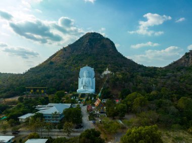 Görkemli bir Buda heykeli yemyeşil tepeler ve doğal ışık arasında meditasyon yapıyor. Bu huzurlu yer, kutsal mimarinin ve doğal güzelliğin uyumunu sergiliyor. dağ arkaplanı