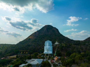 Görkemli bir Buda heykeli yemyeşil tepeler ve doğal ışık arasında meditasyon yapıyor. Bu huzurlu yer, kutsal mimarinin ve doğal güzelliğin uyumunu sergiliyor. dağ arkaplanı