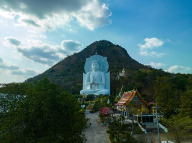 Görkemli bir Buda heykeli yemyeşil tepeler ve doğal ışık arasında meditasyon yapıyor. Bu huzurlu yer, kutsal mimarinin ve doğal güzelliğin uyumunu sergiliyor. dağ arkaplanı