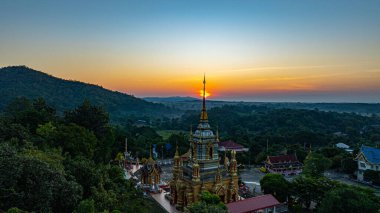 Chiang Mai Tayland 'daki Wat Mae Klang Şelalesi' ndeki altın bir Budist tapınağının nefes kesici hava manzarası yemyeşil, güneşin doğuşu ufuk boyunca sıcak renkler döküyor.. 