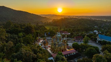 Chiang Mai Tayland 'daki Wat Mae Klang Şelalesi' ndeki altın bir Budist tapınağının nefes kesici hava manzarası yemyeşil, güneşin doğuşu ufuk boyunca sıcak renkler döküyor.. 
