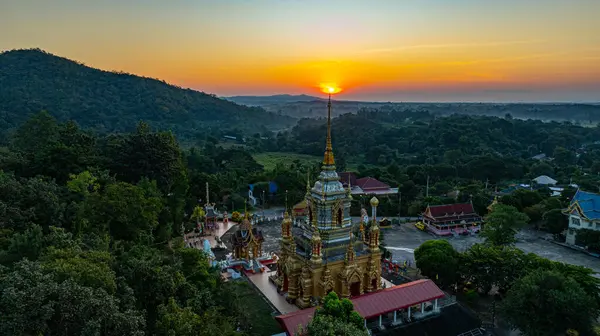 Gün doğumuyla birlikte Chiang Mai 'deki Mae Klang Şelalesi Tapınağı' nın hava görüntüsü sakin gökyüzünde sıcak renkler bırakıyor. Huzurlu ortam, tapınağın ve doğal manzaranın dingin güzelliğini vurguluyor..