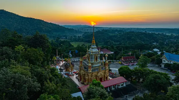 Chiang Mai Tayland 'daki Wat Mae Klang Şelalesi' ndeki altın bir Budist tapınağının nefes kesici hava manzarası yemyeşil, güneşin doğuşu ufuk boyunca sıcak renkler döküyor.. 