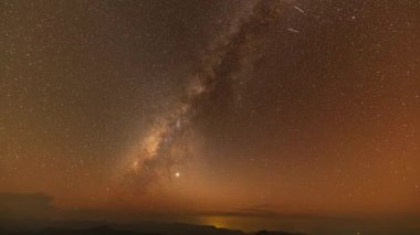 Sonbaharda gece vakti Samanyolu 'nun dağların üzerinde süratle ilerler. Dağ vadisiyle manzara, alçak bulutlar, Samanyolu ile mor yıldızlı gökyüzü. Samanyolu Tayland 'ın kuzeyinde soğuk bir gecede parlıyor.