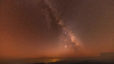 Sonbaharda gece vakti Samanyolu 'nun dağların üzerinde süratle ilerler. Dağ vadisiyle manzara, alçak bulutlar, Samanyolu ile mor yıldızlı gökyüzü. 