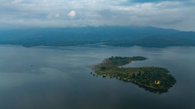 Doi Tao Gölü 'nün ortasındaki bir adadaki tapınağın havadan görünüşü bulutları ve dağları yansıtan sessiz yeşil bir göl.. 