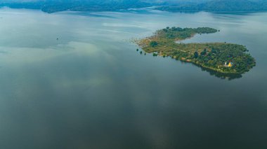 Doi Tao Gölü 'nün ortasındaki bir adadaki tapınağın havadan görünüşü bulutları ve dağları yansıtan sessiz yeşil bir göl..