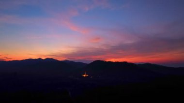 Lampang Tayland 'daki dağda Phra Yai Wat Phra Doi Phra Chan' ın (Daibutsu) üzerinde alacakaranlıkta inanılmaz gökyüzü manzarası. Şok edici günbatımı, dağlık arazide canlı renkler bırakıyor..