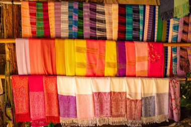Karmaşık desenlere sahip kalın ve zengin renklerden oluşan geleneksel el dokuması kumaşların canlı bir gösterisi. Kuzeydeki dokuma geleneklerinin zanaatkarlığı ve kültürel mirası