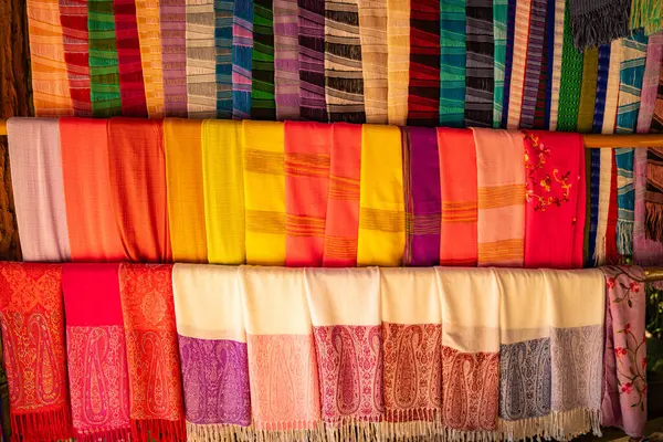 Karmaşık desenlere sahip kalın ve zengin renklerden oluşan geleneksel el dokuması kumaşların canlı bir gösterisi. Kuzeydeki dokuma geleneklerinin zanaatkarlığı ve kültürel mirası