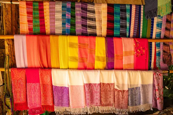 Karmaşık desenlere sahip kalın ve zengin renklerden oluşan geleneksel el dokuması kumaşların canlı bir gösterisi. Kuzeydeki dokuma geleneklerinin zanaatkarlığı ve kültürel mirası