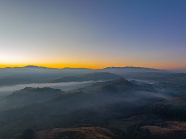 Güzel güneş, vadide sislerin üzerinde parlıyor. Sis bulutu dağın tepesini kaplıyor. Sis denizi gibi. Mükemmel ormanın üzerinde mavi gökyüzünde beyaz bulut.
