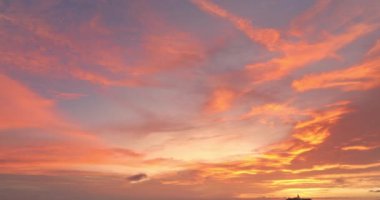 Gün batımında yumuşak pastel renklerle yıkanan Phuket adalarının hava manzarası. Aşağıdaki sakin deniz adalarla dolu, yukarıdaki gökyüzü ise narin pembe ve turuncu bulutlarla boyanmış..