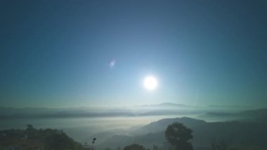 Hızla yükselen güzel güneş, vadide sislerin üzerinde parlıyor. Sis bulutu dağın tepesini kaplıyor. Sis denizi gibi. Mükemmel ormanın üzerinde mavi gökyüzünde beyaz bulut.