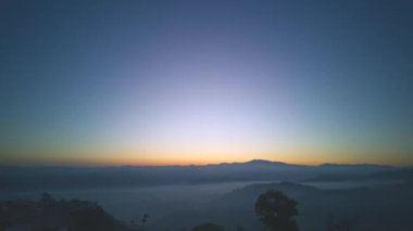 Zaman su gibi akıp geçiyor vadideki sislerin üzerinde. Ufukta güneşin parlak ışığının sebep olduğu tatlı bir gökyüzü var. Güneşin renkli gökyüzü.