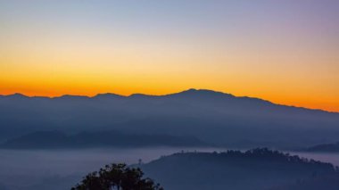 Zaman su gibi akıp geçiyor vadideki sislerin üzerinde. Ufukta güneşin parlak ışığının sebep olduğu tatlı bir gökyüzü var. Güneşin renkli gökyüzü.