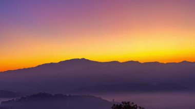 Zaman su gibi akıp geçiyor vadideki sislerin üzerinde. Ufukta güneşin parlak ışığının sebep olduğu tatlı bir gökyüzü var. Güneşin renkli gökyüzü.