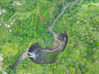 Havadan bakıldığında, Coban Sriti Şelalesi, vadiden aşağı akan ikiz şelale deresi. Su, göz alabildiğince sarmal dağ sırtlarına aktı. yeşil orman  