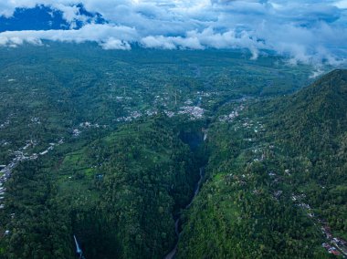 Doğu Java 'da Kabut Pelangi Şelalesi havadan görünüyor. Şelale deresi uzun bir yoldan dağ geçidine akar. Yukarıda köylülerin evi bulunur. Yeşil dağdaki ormanların bolluğu.
