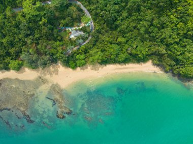 Sarmal yolları, kristal berraklığında turkuaz suları ve parçalı bulutlu bir gökyüzünün altındaki uzak adaları olan yemyeşil bir kıyı şeridinin nefes kesici hava manzarası. Lam Nga Silay Adası 'nda, Phuket. yeşil deniz