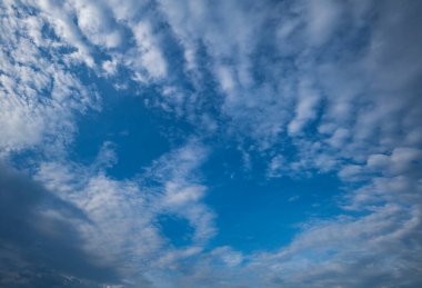 Mavi gökyüzünde beyaz bulutlar Güneş parlıyor.