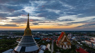 Hava Wat Ketmadi Sriwararam perspektifi bulutlu mavi gökyüzü altında şehir ve kırsal alanlarla çevrili büyüleyici bir Tayland tapınak kompleksi sergiliyor..