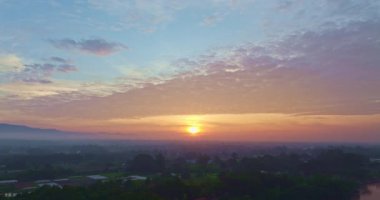 Nefes kesen bir gün doğumu, yemyeşil tarlaların ve karst dağlarının arasına kurulmuş, gökyüzünü dolduran canlı bulutlarla dolu küçük bir köyü aydınlatıyor. Kırsal yaşamın ahengi dramatik doğal oluşumlar oluşturdu.