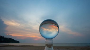 Gün batımında kristal küreye deniz manzarasının zaman aşımı yansıması