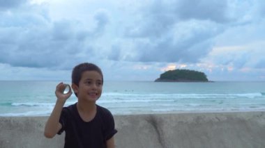 Gün batımında Kata Sahili 'ndeki Phuket Tayland' da kristal küreyi elinde tutan bir çocuk. Mutlu çocuğun gülümseyen yüzü konsepti..