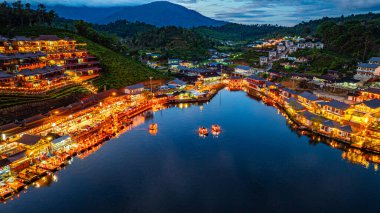 Baan Rak Tayland Köyü, gün batımında Çin tarzı mimaride göl kenarındaki ev ve restoranların renkli ışıklarla yansıması. Mae Hong Son 'da popüler bir turizm merkezi.