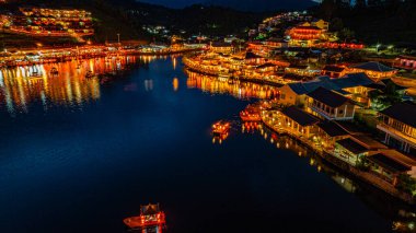 Alacakaranlıkta, köyden gelen ışıkların yansımaları Çin tarzı renkli ışıklı yapılar halinde göl kıyılarını kaplıyordu. Ban Rak Thai, Mae Hong So 'da popüler bir turistik merkezdir.