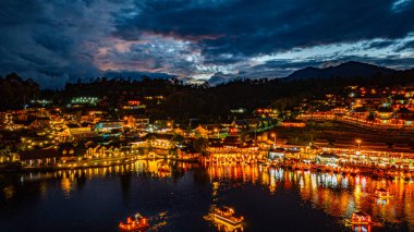 Baan Rak Thai Köyü, gün batımında Çin tarzı mimaride göl kenarındaki ev ve restoranların renkli ışıklarla yansıması.. 