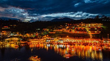 Baan Rak Tayland Köyü, gün batımında Çin tarzı mimaride göl kenarındaki ev ve restoranların renkli ışıklarla yansıması. Mae Hong Son 'da popüler bir turizm merkezi.