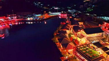 Alacakaranlıkta bir Çin köyünde gölün kenarında ışıklar..