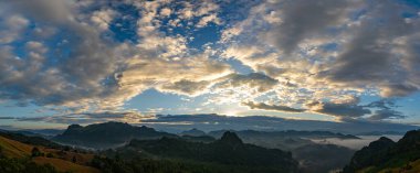 Hava manzarası, sisli bir dağ manzarasının üzerinde şafak vakti nefes kesici bir manzara, sisli katmanlarla. 