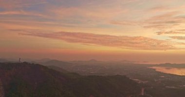 Dağın üzerinden gün doğumunu gösteren hava manzarası. Denizin üzerinde güneşli bir manzara. Horizon Panorama Dağı ve dramatik gökyüzü ve bulutlu gündoğumu arka planı. Doğa videosu çok kaliteli. Chalong Körfezi.
