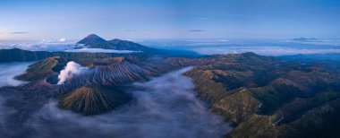 Bromo Dağı 'nın nefes kesici hava manzarası Endonezya' da aktif bir volkan, sis ve dramatik manzaralarla çevrili. Yumuşak sabah ışığı engebeli araziyi ve yükselen volkanik alanı vurguluyor. 
