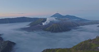 Bromo Dağı 'nın hava manzarası. Etrafı sis ve dramatik manzaralarla çevrili. Endonezya 'da aktif bir volkan yumuşak sabah ışığı engebeli araziyi ve yükselen volkanik dumanı aydınlatıyor.,.