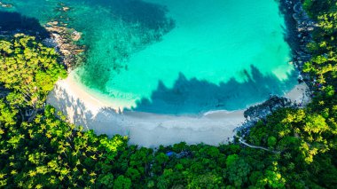 Orman gölgeleri sabahları sahili kaplıyor. Ormanda saklı küçük beyaz bir sahil ve yeşil deniz. Ziyaret etmek zor. Özgürlük Kumsalı ünlü turistik merkezin yakınında Patong..