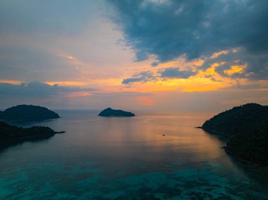 Surin Adaları 'ndaki Mai Ngam Plajı' ndaki tropikal bir sahil şeridinde gün batımının hava hiper yanılma görüntüsü. Gökyüzünün altın rengi suyu yansıtıyor, sakin ve resimsi bir deniz manzarası yaratıyor..