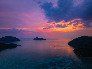 Surin Adaları 'ndaki Mai Ngam Plajı' ndaki tropikal bir sahil şeridinde gün batımının hava hiper yanılma görüntüsü. Gökyüzünün altın rengi suyu yansıtıyor, sakin ve resimsi bir deniz manzarası yaratıyor..