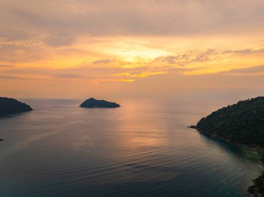 Güneşin Ao Mai Ngam, Surin Adaları 'ndan batışını gösteren hava manzarası. Batan güneşin yansıması. Bereketli yeşil tepeler ve demirlemiş yelkenlilerin silueti huzurlu ortamı geliştirirken.
