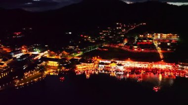 Alacakaranlıkta, köyden gelen ışıkların yansımaları Çin usulü renkli ışıklı yapılar halinde göl kıyılarını kaplıyordu. Ban Rak Thai, Mae Hong Son 'da popüler bir turistik merkezdir.