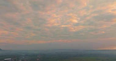 Güneşin doğuşunun havadan görünüşü bulutları aydınlatıyor sisli dağın tepesinde