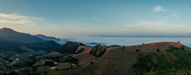 Sabah dağların zirvelerinden gelen ışık ışınlarının havadan görünüşü. Güzel gündoğumu yeşil tepelerin üzerine altın bir parıltı saçıyor. yemyeşil arazide sıcak bir parıltı yayıyor. İnanılmaz manzara 