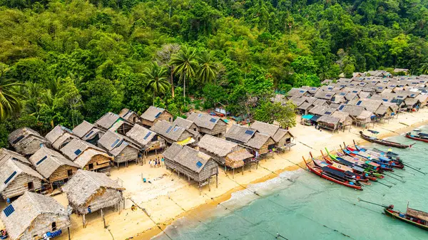 Phang Nga, Tayland-Mart, 20.2025: Yeşillik yeşil ormanlarla çevrili kıyı şeridi boyunca sıralanmış küçük kulübeleriyle tropikal bir sahil Morgan köyünün çarpıcı hava manzarası. Balıkçı tekneleri demirli. 