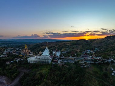 Gün batımında muhteşem Büyük Beyaz Buda Heykelleri 'nin hava manzarası. Wat Phachonkeaw 'un güzel altın köşkü Tayland' ın çok güzel ve ünlü bir simgesi olan tepede mücevherler ve taşlarla süslenir..