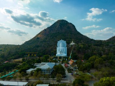 Görkemli bir Buda heykeli yemyeşil tepeler ve doğal ışık arasında meditasyon yapıyor. Bu huzurlu yer, kutsal mimarinin ve doğal güzelliğin uyumunu sergiliyor. dağ arkaplanı