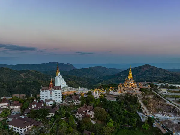 Gün batımında muhteşem Büyük Beyaz Buda Heykelleri 'nin hava manzarası. Wat Phachonkeaw 'un güzel altın köşkü Tayland' ın çok güzel ve ünlü bir simgesi olan tepede mücevherler ve taşlarla süslenir..