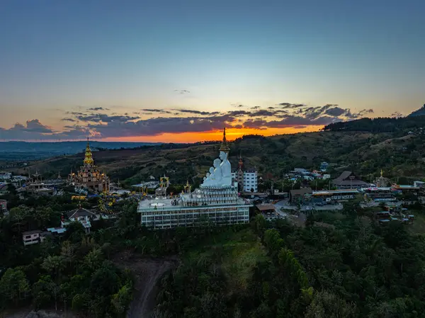 Gün batımında muhteşem Büyük Beyaz Buda Heykelleri 'nin hava manzarası. Wat Phachonkeaw 'un güzel altın köşkü Tayland' ın çok güzel ve ünlü bir simgesi olan tepede mücevherler ve taşlarla süslenir..